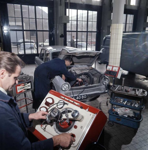 Kijkje in de reparatiewerkplaats van de RAC aan de 1e v.d. Kunstraat. Door de ramen zie je aan de overkant de halfronde hal, ca. 1970. RAC, werkplaats, 1e van der Kunstraat, 1970
